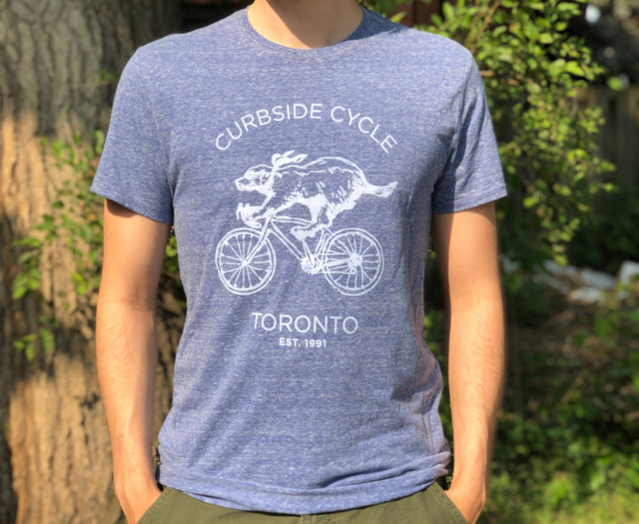 Curbside Cycle Cycling Badger T-Shirt in Colour Blue on Male Model Outside in the Sun