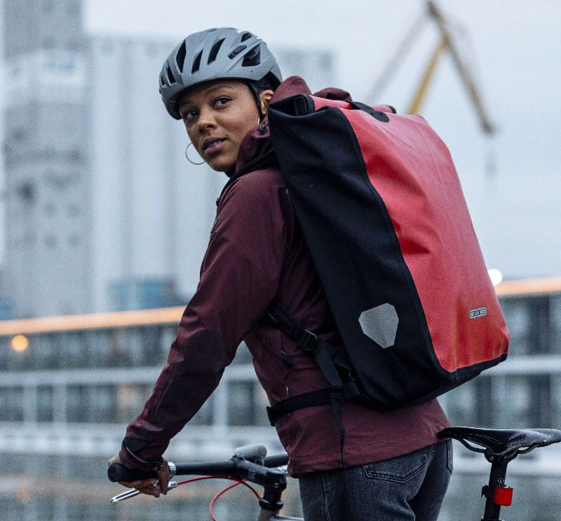 Ortlieb Backpack Messenger Bag in Colour Red and Black Pictured on Cyclist Riding a Bike in the City