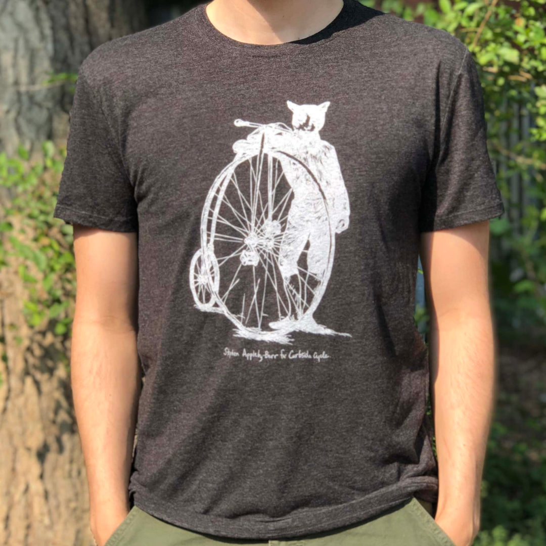 Curbside Cycle 'Cat With Penny-Farthing Bicycle' T-Shirt in Colour Black on Male Model Outside in the Sun